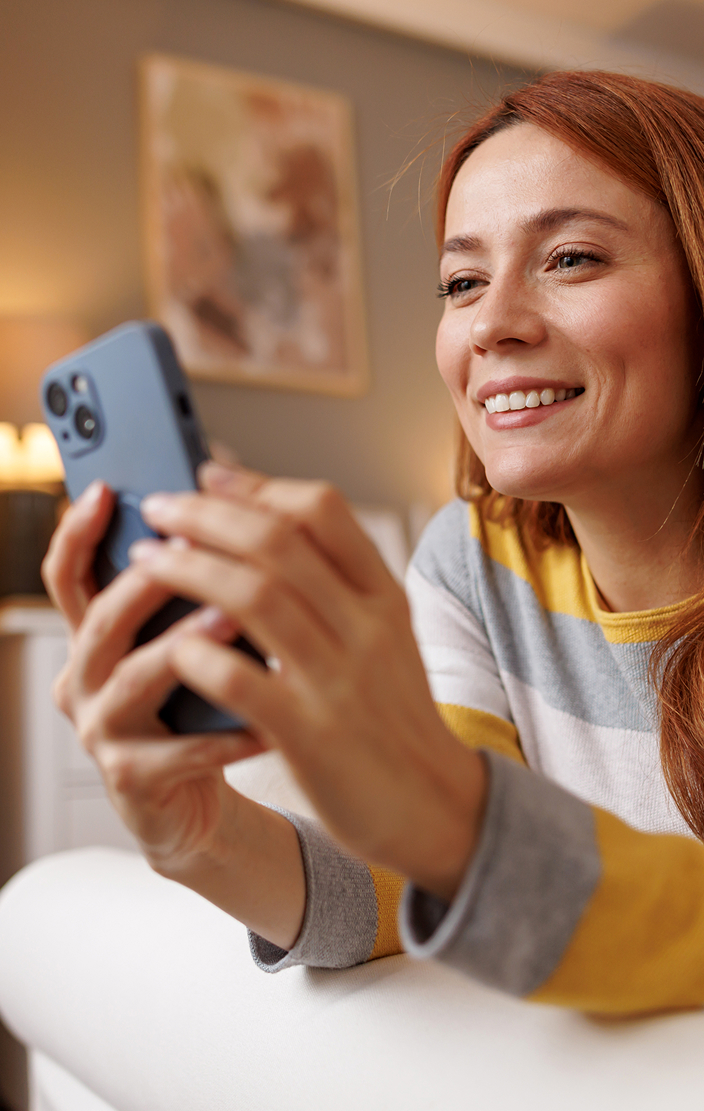 A woman with red hair looking at her iPhone.